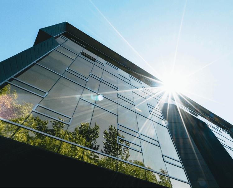 MBM Metalworks｜Facade and Building Envelopes｜Building Integrated Photovoltaics｜Glass building reflects trees in shining Sun